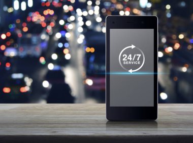 şehir araçları, tam zamanlı hizmet online anlayışı ile 24 saat hizmet düz ahşap masa üzerinde modern akıllı cep telefonu ekran simgesine bulanıklık renkli gece ışık