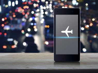 Uçak düz ahşap masa üzerinde modern akıllı cep telefonu ekran simgesine bulanıklık arabalar, iş uçak ulaşım online kavramı ile renkli gece ışık şehir
