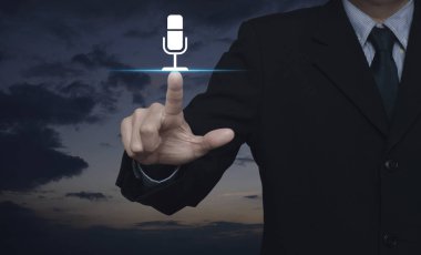 Mikrofon düz simgesi üzerinde günbatımı gökyüzü, iletişim iş kavramı basarak işadamı