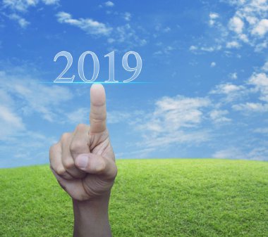 Mavi gökyüzü, mutlu yeni yıl 2019 kavramı ile yeşil çim alanın üzerinde 2019 metin basarak el