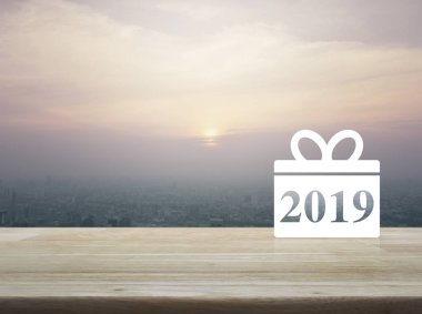 Hediye kutusu mutlu yeni yıl 2019 düz üstünde kutsal kişilerin resmi üzerinde modern şehir kule ve gökdelen günbatımı, vintage tarzı, ahşap masa, iş alışveriş online kavramı