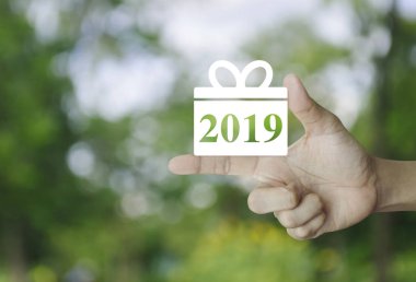 Hediye kutusu mutlu yeni yıl 2019 düz kutsal kişilerin resmi üstünde parmak üzerinde bulanıklık Park, alışveriş online kavramı iş yeşil ağaç