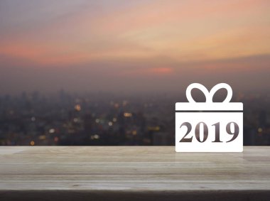 Hediye kutusu mutlu yeni yıl 2019 simgesine ahşap masa üzerinde bulanıklık cityscape sıcak ışık sundown, iş salonu online kavramı