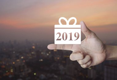 Hediye kutusu mutlu yeni yıl 2019 simgesine parmak üzerinde bulanıklık cityscape sıcak ışık sundown, iş alışveriş online kavramı