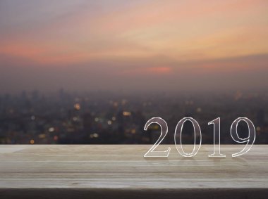 Mutlu yeni yıl 2019 metin üzerinde ahşap masa üzerinde bulanıklık cityscape sıcak ışık sundown, iş tebrik kartı kavramı
