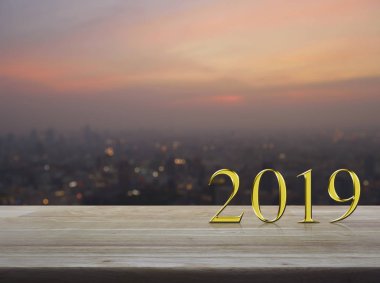 Mutlu yeni yıl 2019 altın metal metin üzerinde ahşap masa üzerinde bulanıklık cityscape sıcak ışık sundown, iş tebrik kartı kavramı