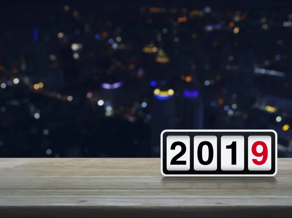 Retro flip clock with 2019 text on wooden table over blur colorful night light modern city tower and skyscraper, Happy new year concept