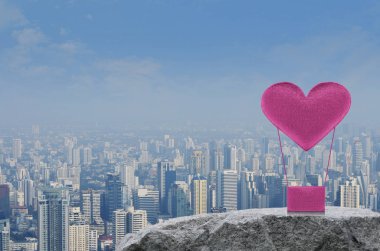Pembe kumaş kalp aşk hava balonu modern şehir Kulesi, Ofis Binası ve gökdelen, Sevgililer günü kavramı üzerinde rock dağda