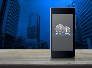 Soru işareti ve ahşap masa ofis şehir kule ve gökdelen, iş müşteri hizmetleri ve destek online kavramı üzerinde modern akıllı cep telefonu ekranda bilgi sohbet simgesini
