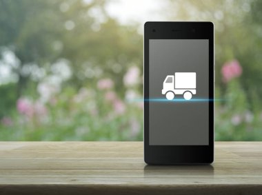 Kamyon teslim düz üstünde kutsal kişilerin resmi ahşap masa üzerinde modern akıllı cep telefonu ekran bulanıklık pembe çiçek ve Bahçe, iş ulaşım online kavramı ağacında