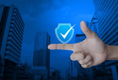Güvenlik kalkanı modern ofis şehir kule ve gökdelen, teknoloji internet siber güvenlik ve anti virüs kavramı üzerinde parmak üzerindeki onay işareti simgesiyle