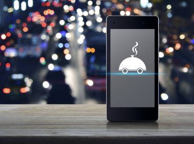 Restoran cloche düz üstünde kutsal kişilerin resmi ahşap masa üzerinde modern akıllı cep telefonu ekran bulanıklık arabalar, iş gıda teslim online kavramı ile renkli gece ışık şehir