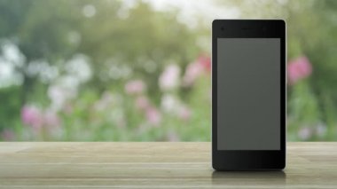 Parkta bulanıklık pembe çiçek ve ağaç üzerinde ahşap masada modern akıllı cep telefonu ekranında 24 saat düz simge açık, İş tam zamanlı hizmet online kavram