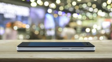Alışveriş merkezibulanıkLık ve gölge üzerinde ahşap masa üzerinde modern akıllı cep telefonu ekranında 24 saat hizmet simgesi, İş tam zamanlı online hizmet konsepti