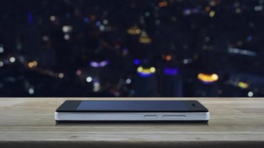 Mikrofon düz ahşap masa üzerinde modern akıllı cep telefonu ekran simgesine bulanıklık renkli gece ışık şehir kule ve gökdelen, online iletişim iş kavramı