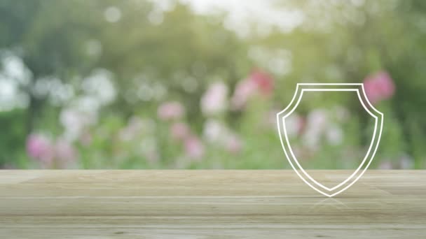 挂锁与盾牌平面图标在木桌上模糊的粉红色花和树在花园里 商业安全保险概念 — 图库视频影像