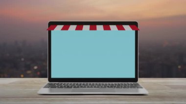 Sıcak ışık günbatımı nda cityscape bulanıklık üzerinde ahşap masa üzerinde online alışveriş mağazası grafik ve açık tabela ile modern dizüstü bilgisayar, İş internet mağazası online kavram