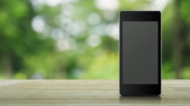 Parkta bulanıklık yeşil ağaç üzerinde ahşap masada modern akıllı cep telefonu ekranında 24 saat düz simge açık, İş tam zamanlı hizmet online kavram