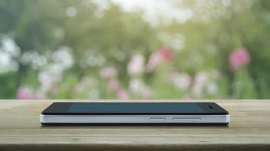 Mikrofon düz ahşap masa üzerinde modern akıllı cep telefonu ekran simgesine bulanıklık pembe çiçek ve ağaç Park, online iletişim iş kavramı