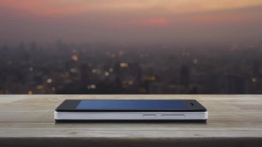Soru işareti simgesi simgesi modern akıllı cep telefonu ekranında ahşap masa üzerinde sıcak gün batımında şehir manzarası bulanıklığı, iş dünyası müşteri hizmetleri ve çevrimiçi konsepti destekleme