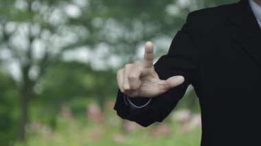 İş adamı parktaki bulanık çiçek ve ağacın üzerine banka resmi bastırıyor, iş bankacılığı online konsepti