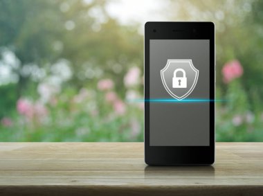 Modern akıllı cep telefonu ekranında, bahçedeki bulanık pembe çiçek ve ağaç üzerinde asma kilit, iş güvenliği sigortası çevrimiçi kavramı