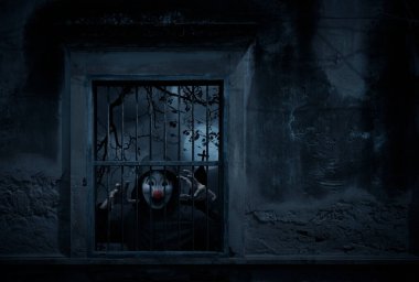 Korkunç kötü palyaço ceketi eski hasarlı pencerede duruyor haçın üzerinde duvar, kilise, kuşlar, ölü ağaç ve ürkütücü bulutlu gökyüzü, Cadılar Bayramı gizemi konsepti