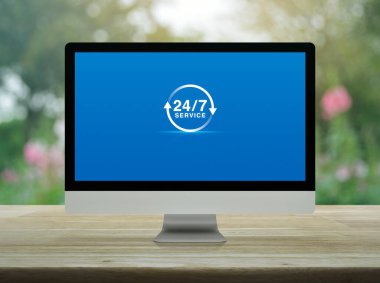 24 saatlik servis düz simgesi masaüstü modern bilgisayar monitörü ekranı ahşap masa üzerinde bulanık pembe çiçek ve ağaç üzerinde bahçe, iş tam zamanlı servis online konsepti