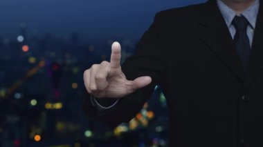 İş adamı, bilgi simgesini bulanık gece aydınlığı, modern şehir kulesi ve gökdelen, iş müşteri hizmetleri ve destek kavramının üzerine basıyor.