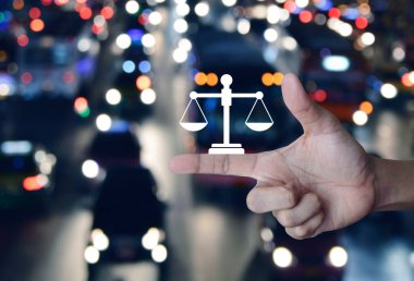 Arabaları, yolları ve iş hukuku hizmetleri kavramları olan bulanık gece lambası şehri üzerinde parmak üstüne hukuk dairesi simgesi.