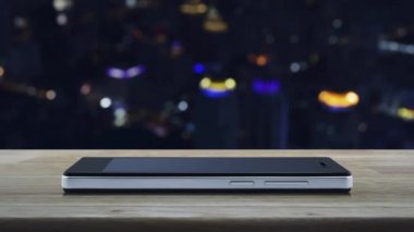 Modern akıllı cep telefonu ekranına düz simge yükle ahşap masa üzerine bulanık renkli şehir kulesi ve gökdelen, teknoloji internet konsepti