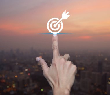 Sıcak gün batımında şehir manzarası bulanıklığı üzerine dart ikonu ile el sıkışan hedef, iş başarısı konsepti