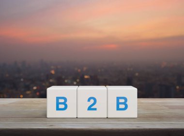 Beyaz blok küpleri üzerinde B2B kısaltması ahşap masa üzerinde şehir manzarası sıcak gün batımında iş dünyasından iş dünyasına ve strateji kavramına