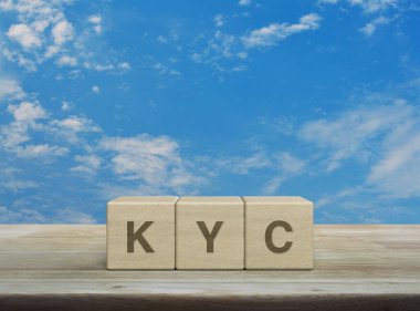 KYC kısaltması ahşap küpler üzerinde ahşap masa üzerinde beyaz bulutlu mavi gökyüzü, müşteri konseptini biliyorum