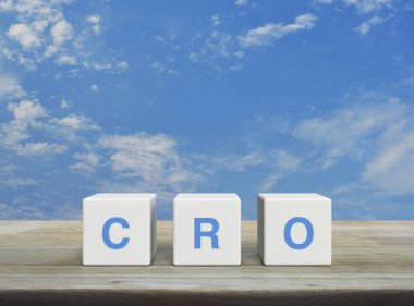 CRO kısaltması beyaz bulutlu mavi gökyüzü üzerinde ahşap masa üzerindeki beyaz blok küpleri, Dönüşüm Oranı İyimserleştirme kavramı