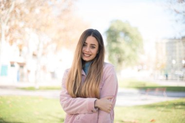 Güven ve iş kavramı. Pembe ceketli, kendine güvenen bir ifadeyle gülümseyen çekici sarışın kadın portresi.