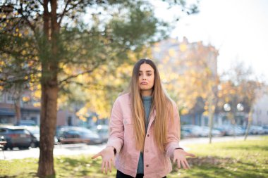 Kafası karışmış, kolları açık, omuzlarını silkip 