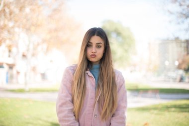 Parkta pembe ceketli güzel sarışın kadın.  