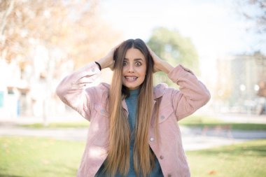 Pembe ceketli güzel sarışın kadın parkta şaşırdı.  