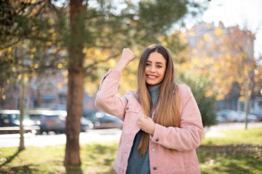Genç ve güzel sarışın hippi kadın, gündelik giysiler giyip çılgınlığı kutluyor ve başarıya hayret ediyor. Kolları açık, gözleri açık, heyecanla bağırıyor. Kazanan konsept. Dışarıda dikiliyorum.