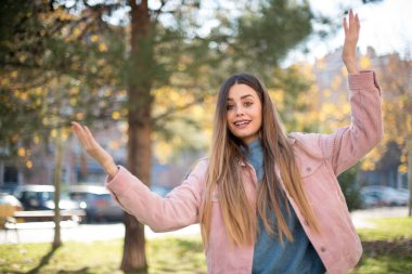 Pembe ceket giyen güzel sarışın kadının portresi kameraya heyecanla bakıyor, ellerini havada tutuyor, beklenmedik bir şey fark ediyor, dışarıda poz veriyor. Güzel bir kadın ani haberlere tepki verir.