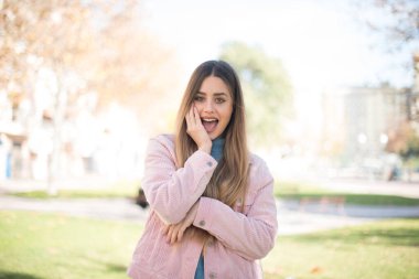 Pembe ceketli güzel sarışın kadın parkta şaşırdı.  