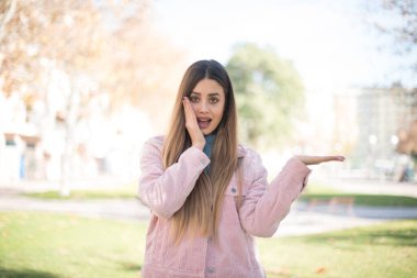 Pembe ceketli güzel sarışın kadın parkta bir şey gösteriyor.  