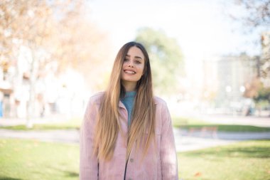 Güven ve iş kavramı. Çekici, başarılı bir kızın portresi, açık havada dururken kendine güvenen bir ifadeyle geniş bir gülümseme.