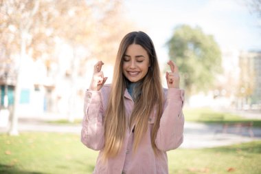 Kazanmak zorundayım. Pembe ceketli neşeli sarışın kadın dişlerini sıkıyor, parmaklarını kaldırıyor, arzu edilen dilekleri diliyor, yuvarlak gözlük takıyor ve sıradan kıyafetler giyiyor, iyi haberleri bekliyor, dışarıda parkta duruyor.