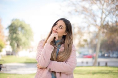 Kasvetli, pembe ceketli genç bir kadının dudaklarının arasına bakıp, önemli bir şey hakkında üzüldüğünü düşünmesi, elini yüzüne yaklaştırmıyor. Sarışın kadın dışarıda duruyor..