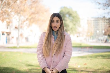 Pembe ceketli güzel sarışın kadının parkta kafası karışmış.  