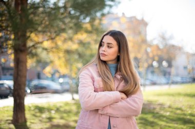 Kolları açık havada duran neşeli, yeşil gözlü genç bir kadının portresi. Güzel beyaz kız kollarını kavuşturarak kendinden emin hissediyor.