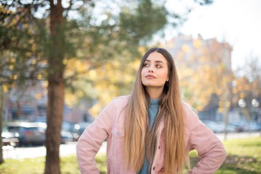 Güven ve iş kavramı. Pembe ceketli, kendine güvenen bir ifadeyle gülümseyen çekici sarışın kadın portresi.