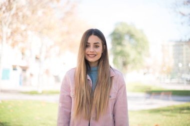 Güven ve iş kavramı. Pembe ceketli, kendine güvenen bir ifadeyle gülümseyen çekici sarışın kadın portresi.